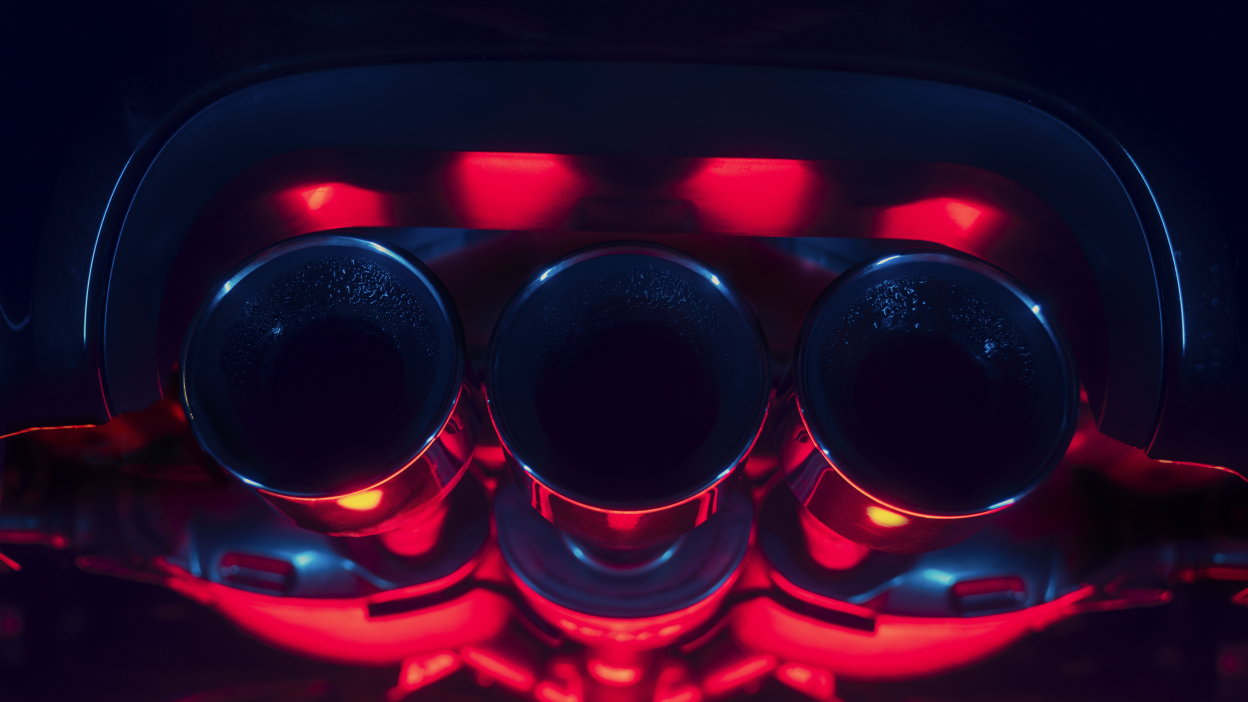 Gros plan de l’échappement triple central d’une Integra Type S. L’image est saturée de lumière rouge et bleue.