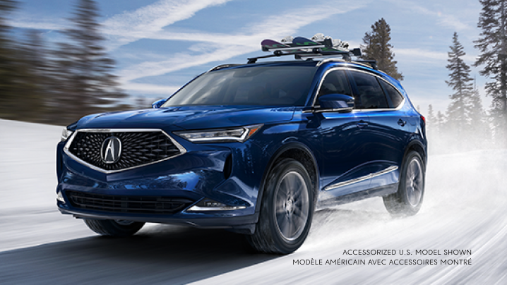 Un MDX bleu avec fixation pour planche à neige circulant sur une route enneigée.