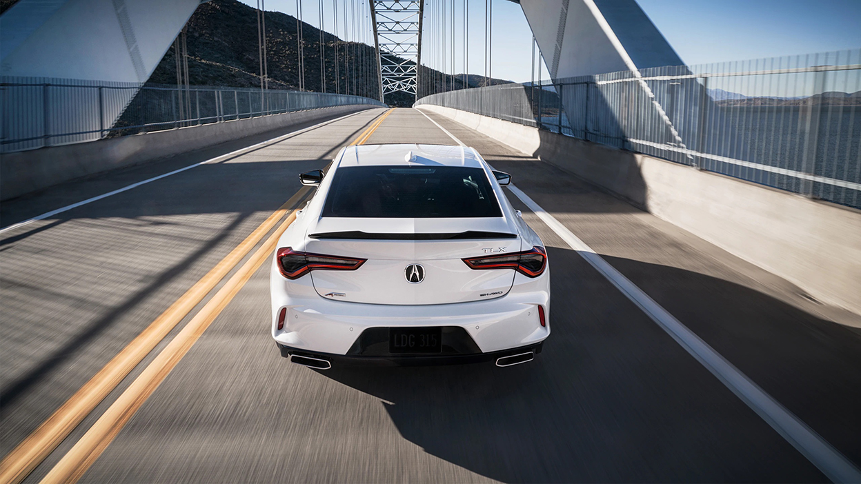 Vue arrière d’une TLX blanche circulant sur un pont.