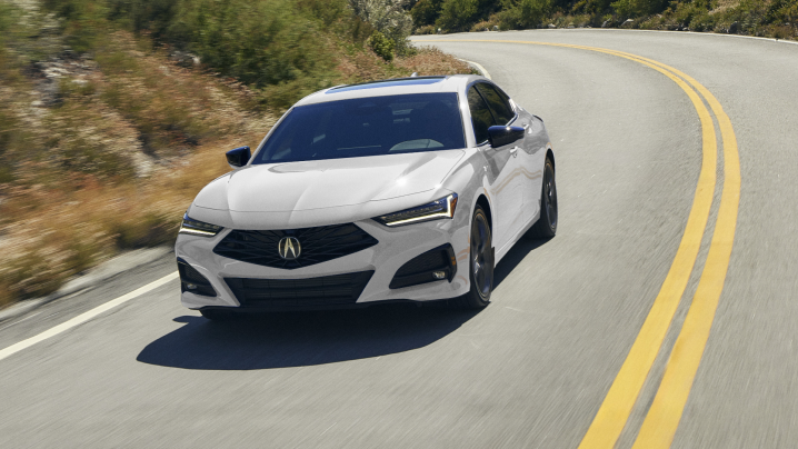 Plan avant d’une TLX blanche prenant un virage sur l’autoroute.