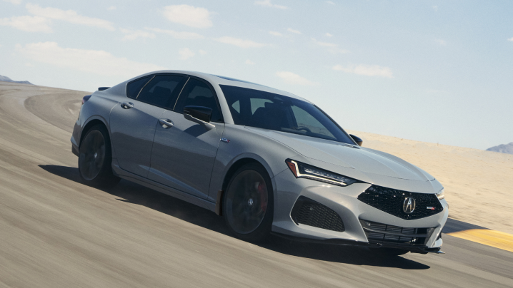 Plan de trois quarts latéral avant d’une TLX Type S grise prenant un virage sur une piste de course dans le désert.