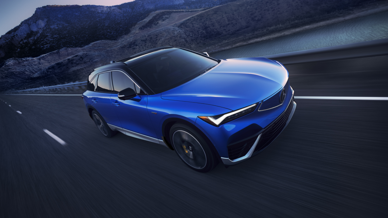 3/4 bird’s eye front view of blue ZDX driving on desert highway at dusk.