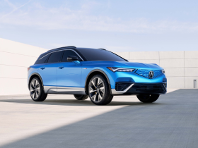 3/4 front view of blue ZDX parked, surrounded by modern, minimalistic architecture.